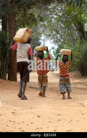 Bambini che raccolgono l'acqua dal pozzetto e portando a casa. Foto Stock