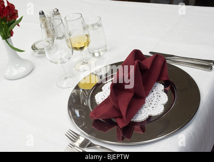 Ristorante di lusso dinner set up, con placca alluminio SILVER, tovagliolo piegato, bicchieri di vino e acqua... Foto Stock