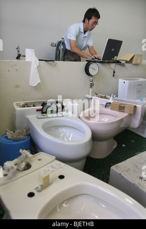 Un dipendente controlla le funzioni di acqua di vari tipi di bagni, nei laboratori di ricerca della Toto. Kokura, Giappone. 08.08.0 Foto Stock