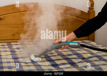 Un uomo con una macchina a vapore sia per pulire e sterilizzare un materasso.  Il vapore può aiutare a uccidere cimici etc Foto stock - Alamy