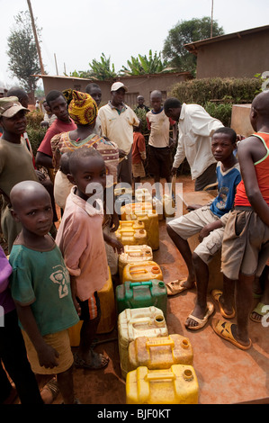 Bambini che raccolgono l'acqua dal pozzetto e portando a casa. Ruanda Foto Stock