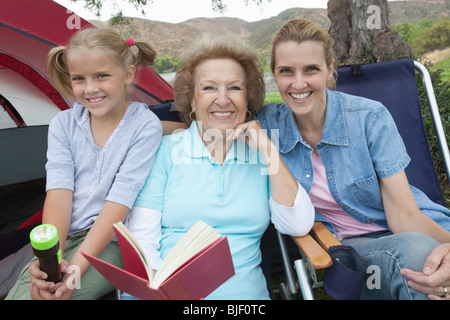 Madre e figlia e grand-figlia sit lettura tenda esterna Foto Stock