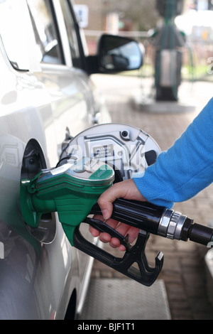 Un automobilista si riempie la sua vettura a benzina da una pompa di benzina. Foto Stock