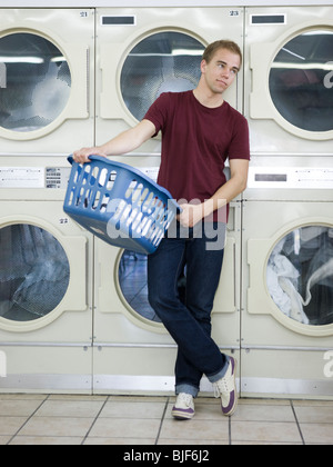 Uomo che fa servizio lavanderia in una lavanderia a gettoni Foto Stock