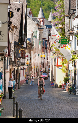 Uomo in bicicletta e people shopping a Bacharach in Renania regione della Germania - Old Street con metà case con travi di legno Foto Stock