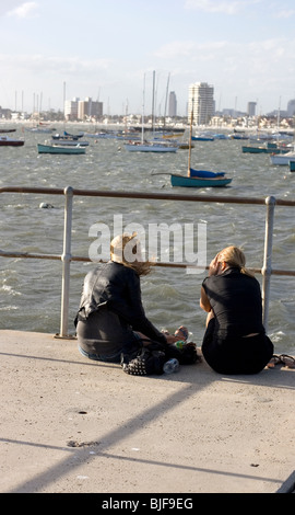 Due amici sedersi e parlare durante una burrasca sul molo Minion, Melbourne, Australia. Foto Stock