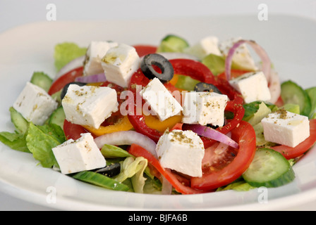 Insalata greca con il formaggio Feta contenente pomodori, cetrioli e lattuga, peperoni e olive nere condite con zaatar Foto Stock