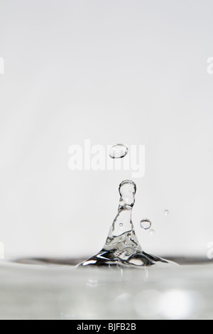 Alta velocità fotografia di una goccia di acqua rimbalzante su una superficie piana di superficie di acqua. Foto Stock