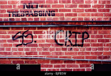 Piuttosto forboding graffiti su un muro di mattoni in un vicoletto. 'SS. CRIP' sotto 'n' tresspassing Foto Stock