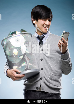 Uomo con un cestino pieno di cd e in possesso di un iPod Foto Stock