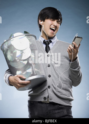 Uomo con un cestino pieno di cd e in possesso di un iPod Foto Stock