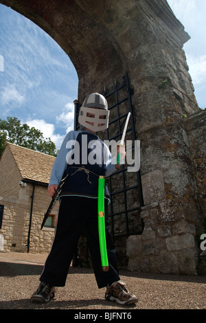 Ragazzo che finge di essere un cavaliere in armatura al di fuori del castello di Carisbrooke sull'Isola di Wight Foto Stock