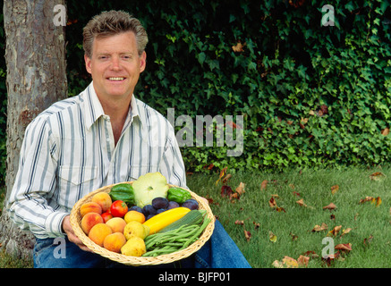 Uomo con verdure e cesto di frutta Foto Stock
