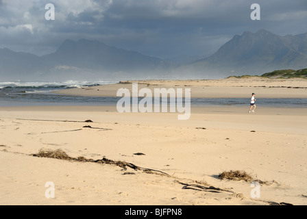 Donna in corsa la mattina da Flamingo estuario del lago vicino a Hermanus, South Western Cape, Sud Africa Foto Stock