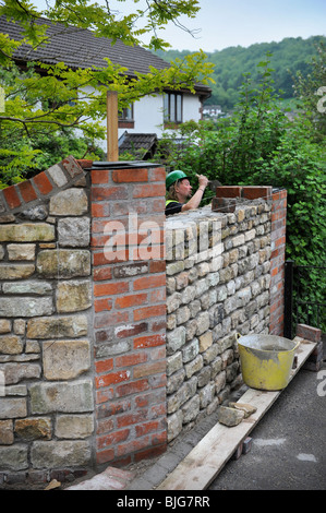 La costruzione di un muro del giardino con cotswold in pietra e malta di cemento con rosso rigenerati pilastri in mattoni ed affrontando REGNO UNITO Foto Stock