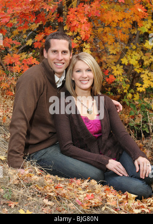 Attraente coppia giovane seduti insieme all'aperto in colori autunnali Foto Stock
