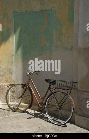 Il vecchio stile bicicletta appoggiata sulla parete colorata Foto Stock