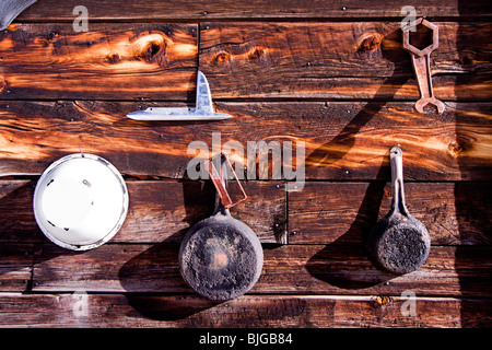 Pentole, padelle e attrezzi assortiti appendere alla parete esterna di una cabina di legno in Guffey, Colorado, Stati Uniti d'America. Foto Stock