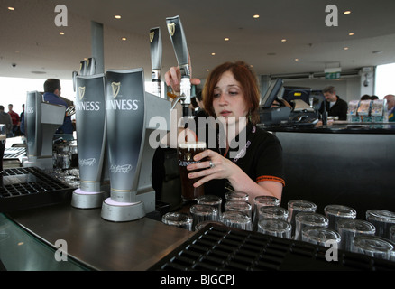 Donna rubinetti birra Guinness in un bar di Dublino, Irlanda Foto Stock