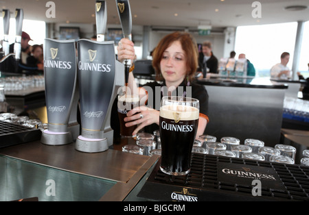 Donna rubinetti birra Guinness in un bar di Dublino, Irlanda Foto Stock