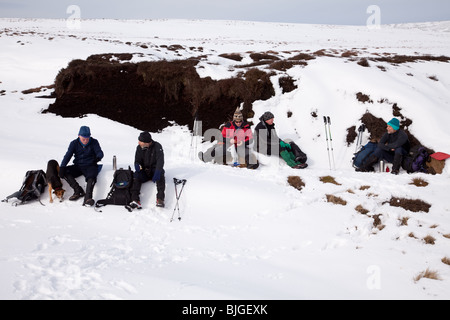 Passeggiate invernali su Bleaklow nel Derbyshire Peak District - una sosta pranzo Foto Stock