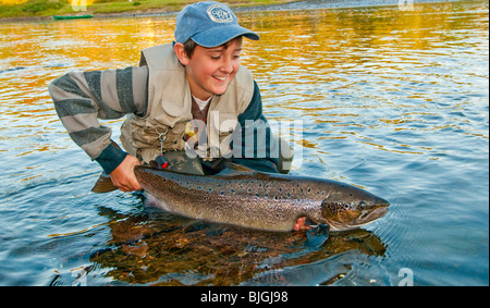 NEW BRUNSWICK pescatore adolescente rilasciando il salmone atlantico sul famoso fiume Miramichi Foto Stock