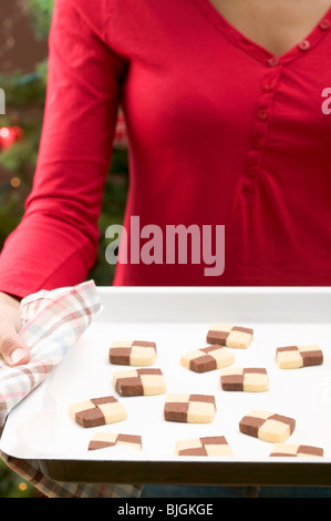 Donna che mantiene il vassoio di cottura di biscotti a scacchiera - Foto Stock