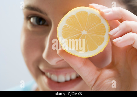 Giovane donna di limone di contenimento nella parte anteriore del suo occhio - Foto Stock