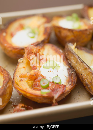 Patate al forno bucce con pancetta e panna acida e anelli di peperoncino - Foto Stock