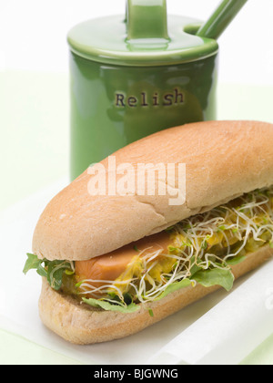 Un hot dog con i germogli accanto a una pentola relish - Foto Stock