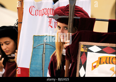 Città italiana di Lucca. Giovani donne locali portano i banner in costume medievale street pageant festival. Toscana, Italia Foto Stock