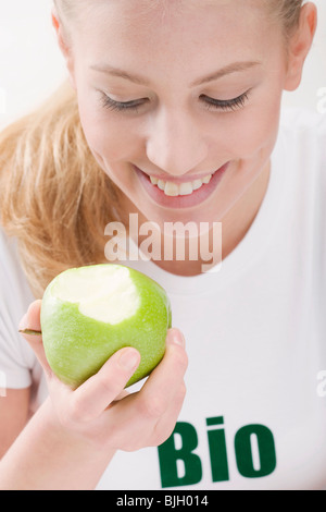 Donna di mangiare un organico di mela verde - Foto Stock