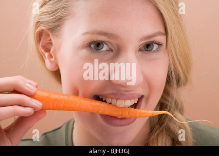 Donna di mordere una carota fresco - Foto Stock