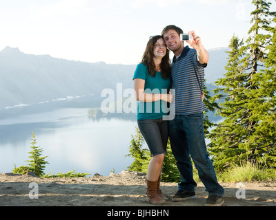 Coppia giovane di scattare una foto di se stessi di fronte ad una vista panoramica che si affaccia su un bellissimo lago Foto Stock
