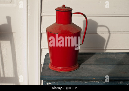 Americana. Immagine di un rosso latte caraffa seduto su un portico nella luce del sole della mattina. Foto Stock