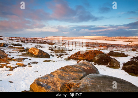 Bordo Curbar illuminato da gli ultimi raggi del sole al tramonto nel distretto di Peak seguenti nevicate invernali Foto Stock