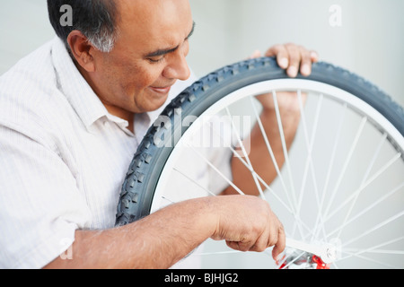 Uomo che ripara bicicletta Foto Stock