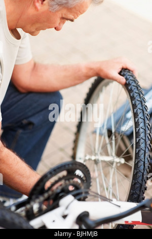 Uomo che ripara bicicletta Foto Stock