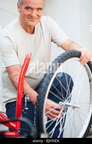 Uomo che ripara bicicletta Foto Stock
