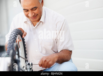 Uomo che ripara bicicletta Foto Stock