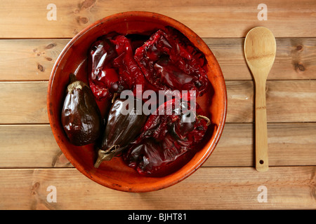 Le melanzane e i peperoni arrostiti sulla tradizionale recipiente di argilla sopra legno Foto Stock