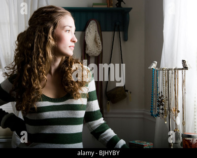 Donna seduta nella sua camera da letto accanto a una finestra Foto Stock