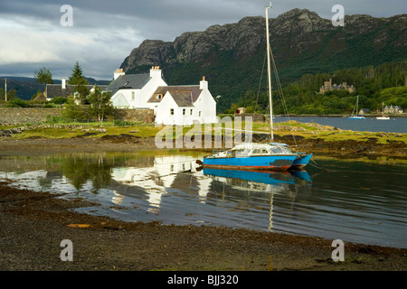 Vecchio trasandato catamarano ormeggiato da casette imbiancate a Plockton Loch Carron Wester Ross Foto Stock