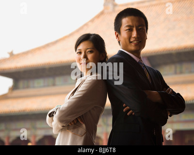 Imprenditore e la donna in piedi con le braccia incrociate e spalle insieme a pagoda in background Foto Stock