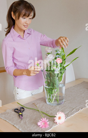 Giovane donna disponendo fiore Foto Stock