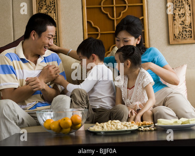 Famiglia avente pillow fight sul divano a ridere Foto Stock