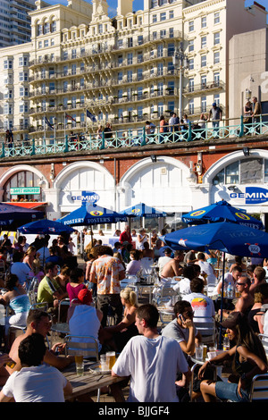 Inghilterra East Sussex Brighton persone ai tavoli sulla promenade Gemini Bar sulla spiaggia con Grand Hotel al di là Foto Stock