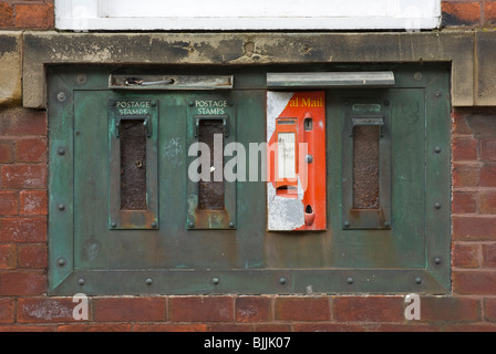 Timbro di vecchia macchina distributrice nella parete di un ufficio postale, Maryport, West Cumbria, England Regno Unito Foto Stock