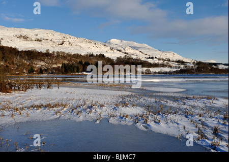 Congelati Loch Tay con circostante coperta di neve sulle colline vicino a Killin, Perthshire, Scotland, Regno Unito Foto Stock