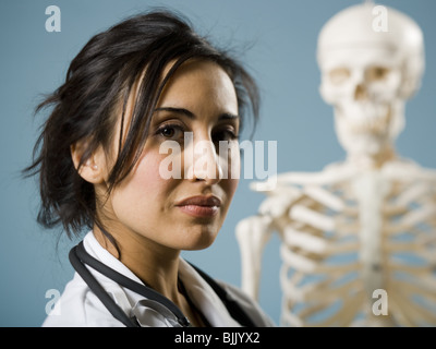 Medico donna sorridente con scheletro in background Foto Stock